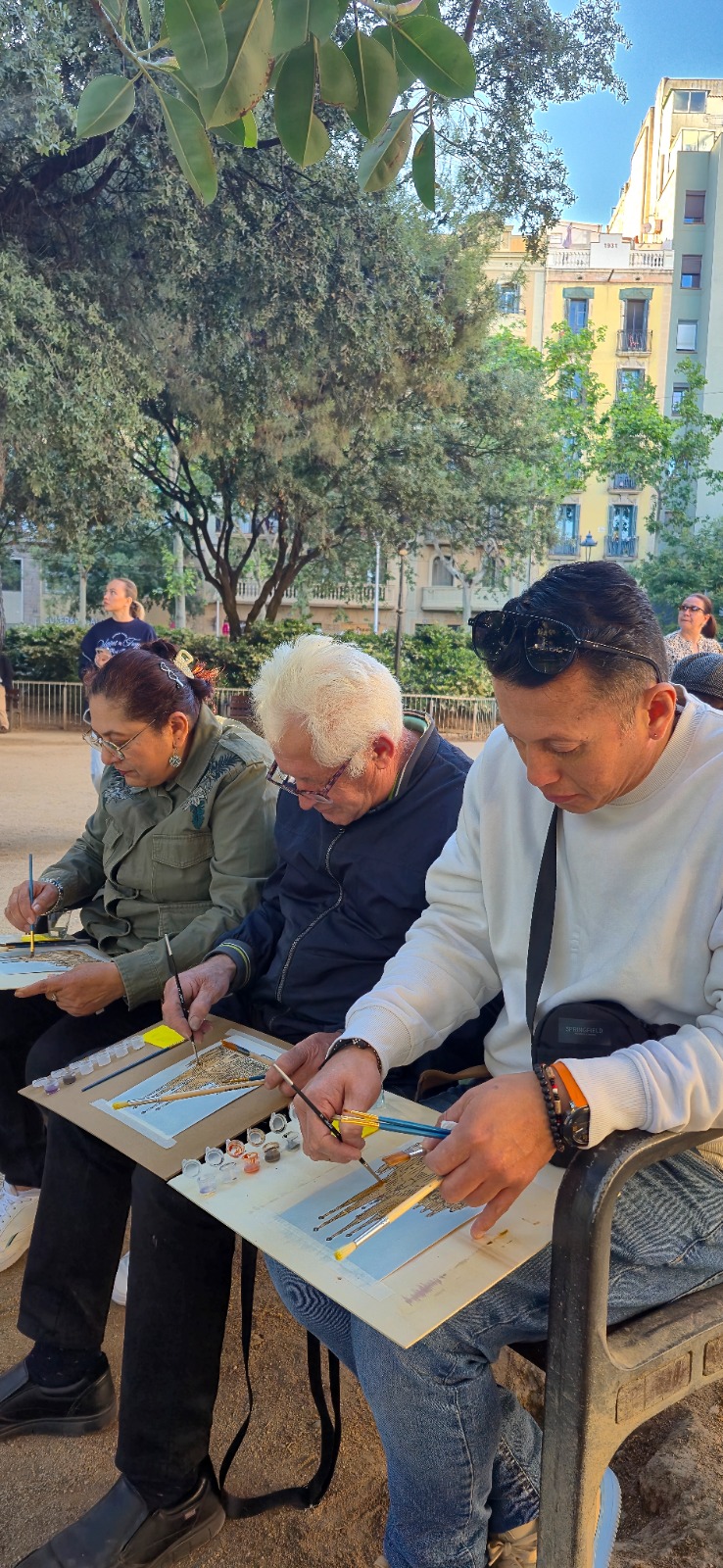 Participantes pintando sus postales en un banco cerca de la Sagrada Família